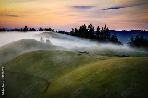 Mist over rolling green  hills at sunset