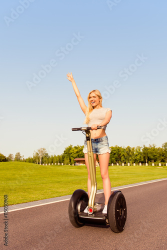 Pretty happy girl with raised hand riding a segway photo