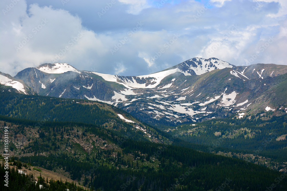 Snow Capped Mountains Above the Tree Line in a Pine Tree Forest in Colorado