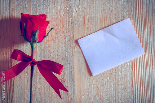 red rose put on white blank paper on wooden background, valentine concept. photo
