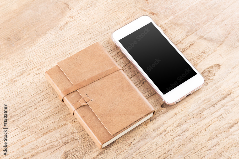 Brown leather notebook and Mobile phone on wood table background Brown leather notebook and Mobile phone on wood table background