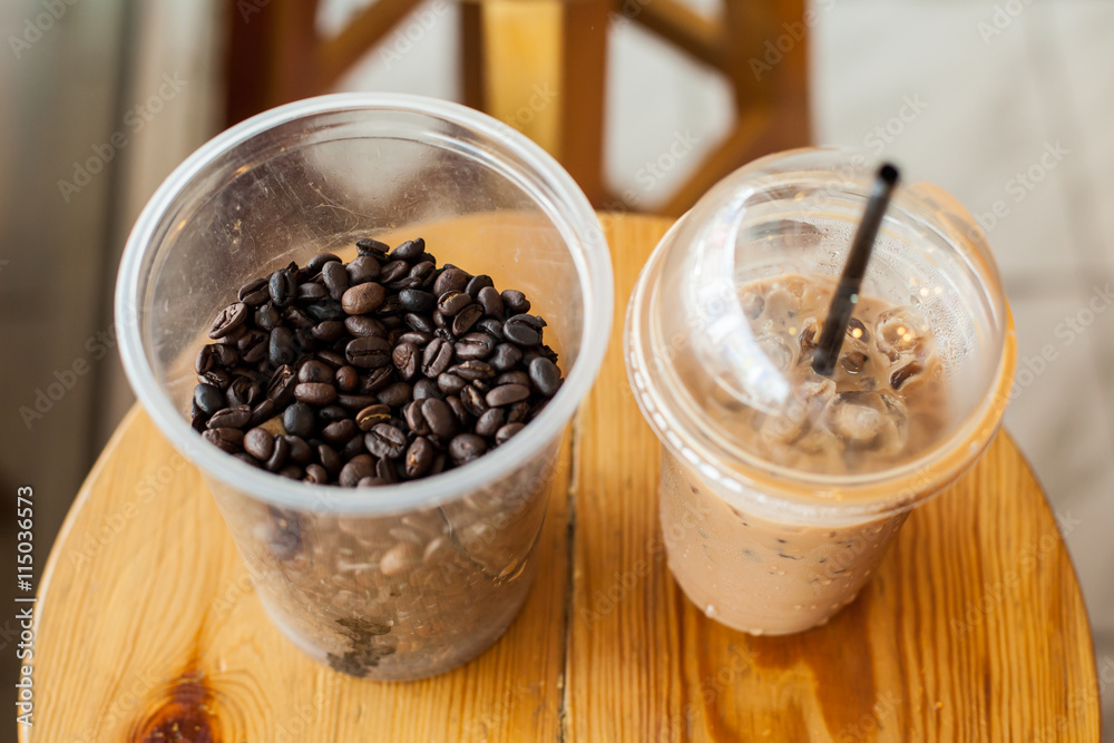 cup of ice coffee with coffee beans on wooden chair cup of ice coffee with coffee beans on wooden chair