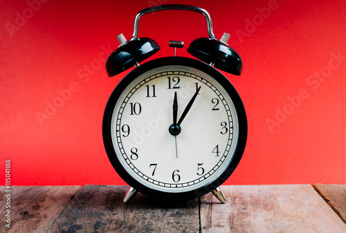 Black alarm clock on wood and red background