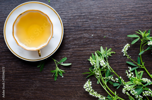 herbal sweetclover tea in a porcelain cup on a dark wooden background