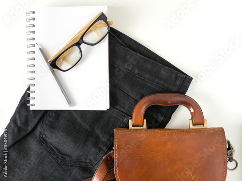 notebook eye glasses pencil and leather bag on white background