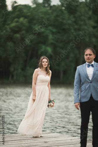 Elegant beautiful wedding couple posing near a lake at sunset © olegparylyak