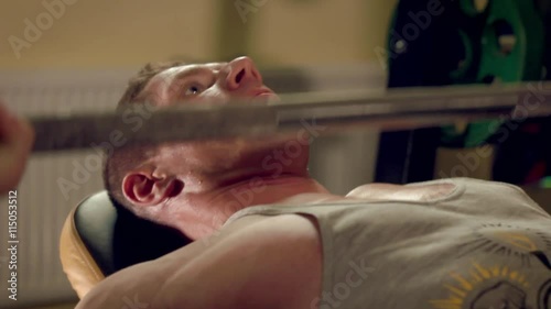 Man doing exercises bench press with a barbell in the gym hand close-up
