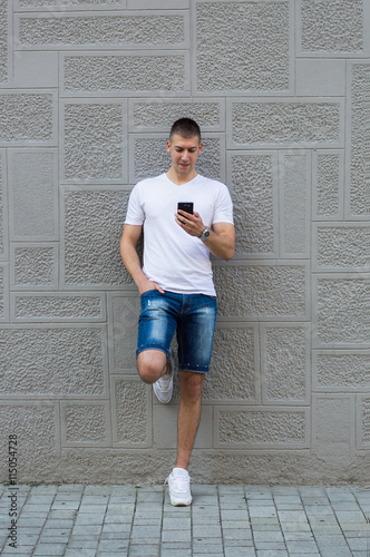 Foto Young casual man using a smart phone texting messages in the str