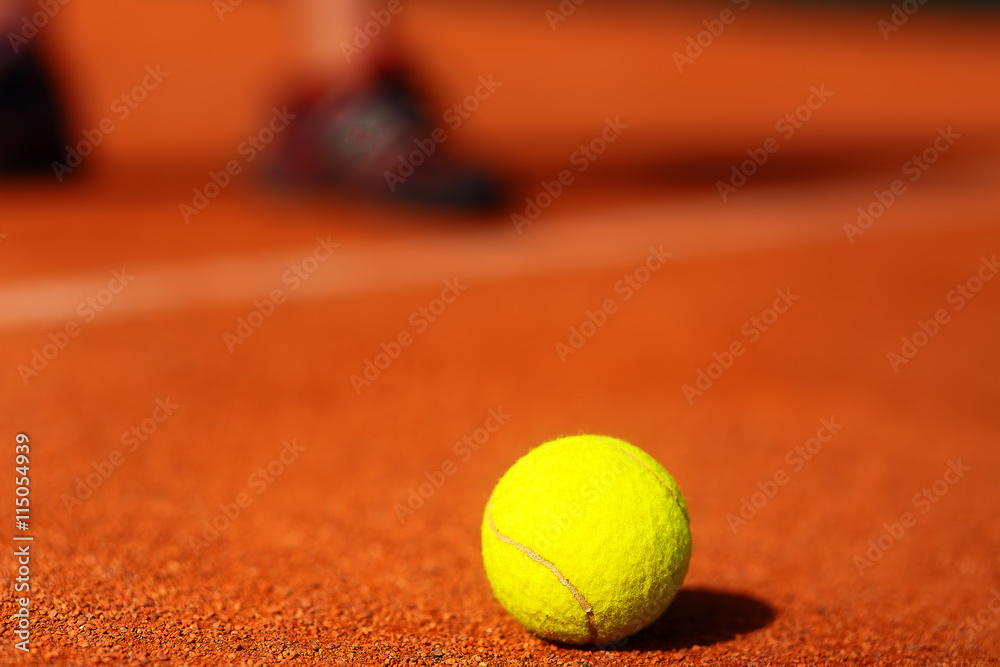 tennis court with tennis ball and man legs on background.