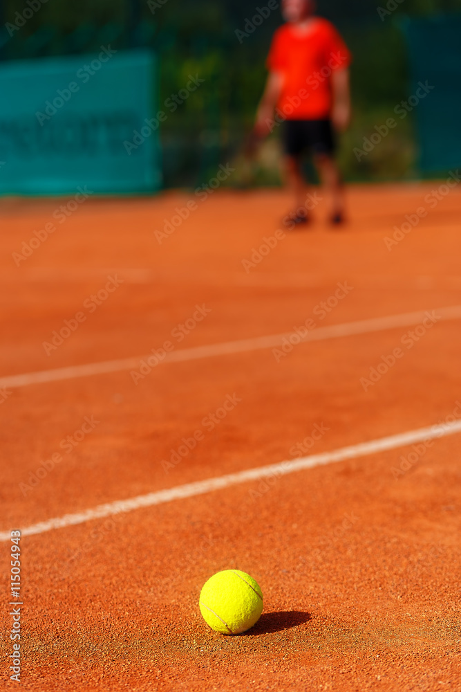 tennis court with tennis ball and man on background.