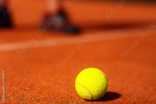 tennis court with tennis ball and man legs on background. © jozefklopacka