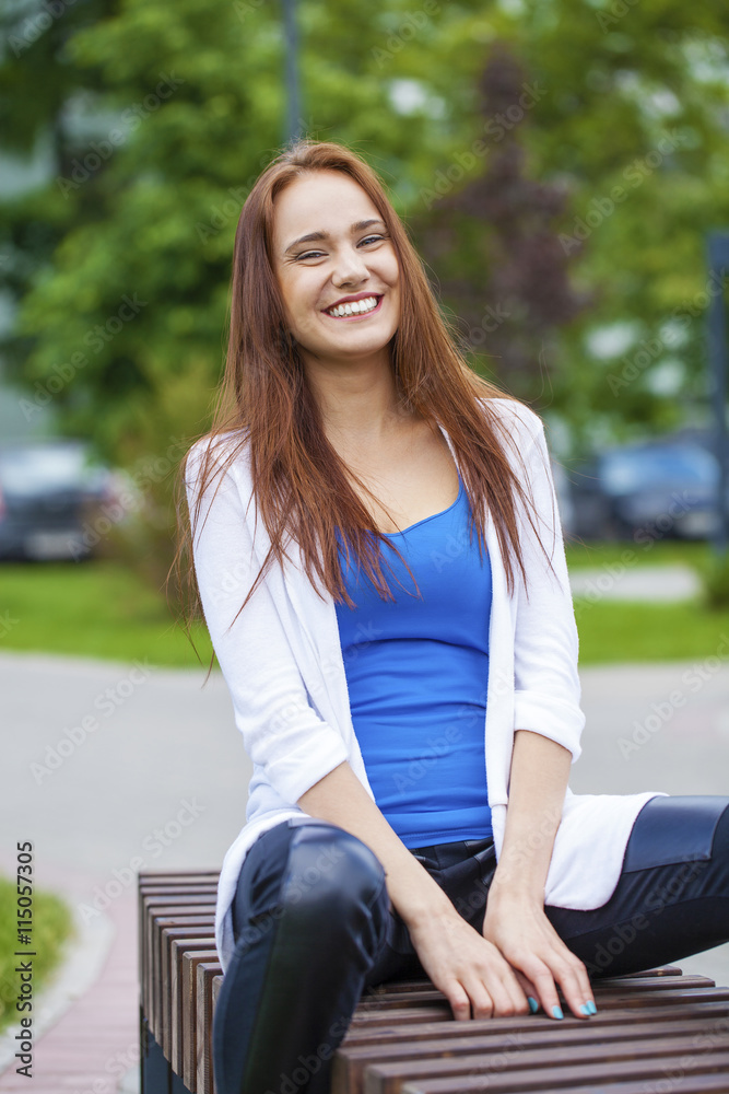 Young beautiful girl sitting on a bench in the summer park Young beautiful girl sitting on a bench in the summer park