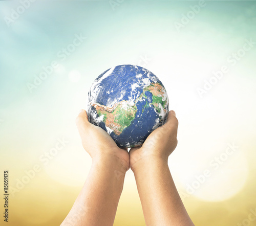 Earth day concept  Earth globe in human hands over blurred nature background. Elements of this image furnished by NASA