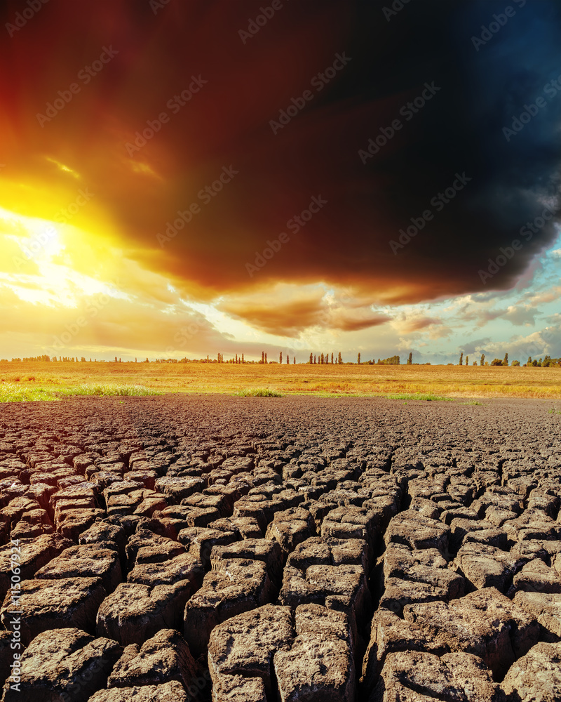 Fototapeta premium low dark clouds in sunset and drought earth closeup