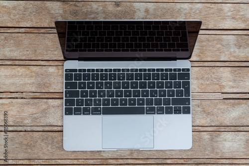 Laptop aufgeklappt oben auf Holztisch