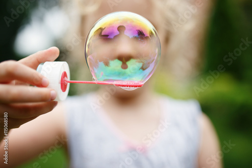 Cute little girl is blowing a soap bubbles and having fun