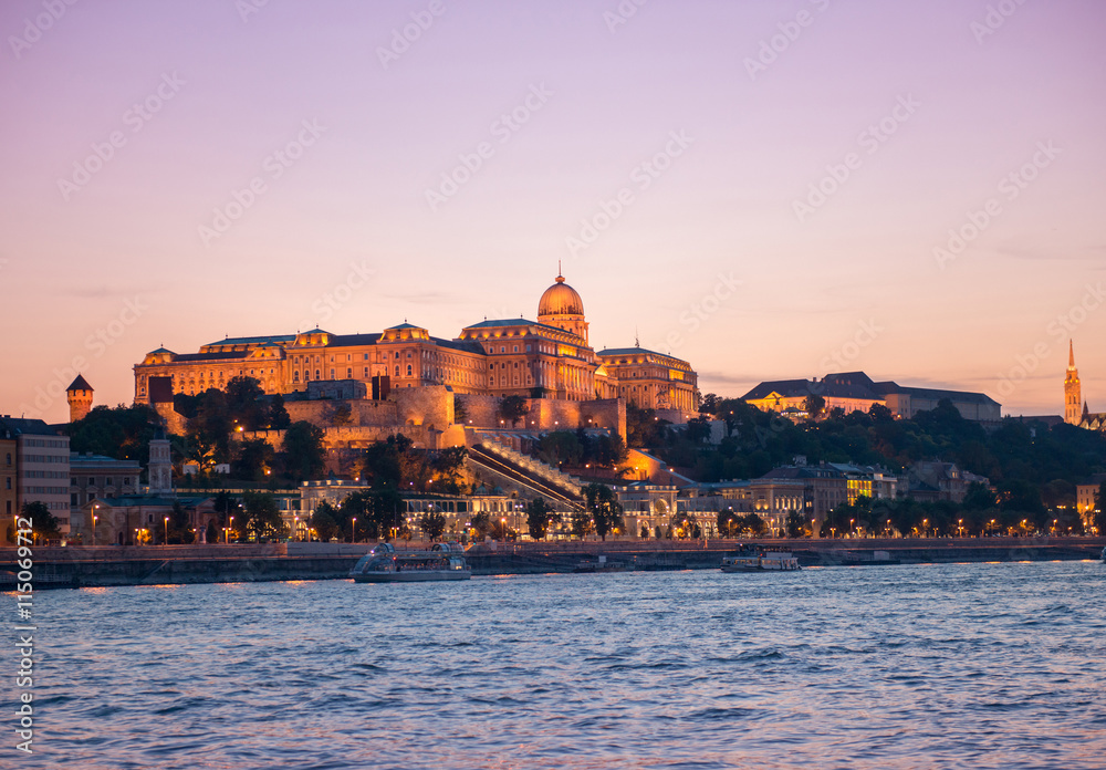 illuminated Budapest Castle at sunset with colorful sky on the background, beautiful view from Danube