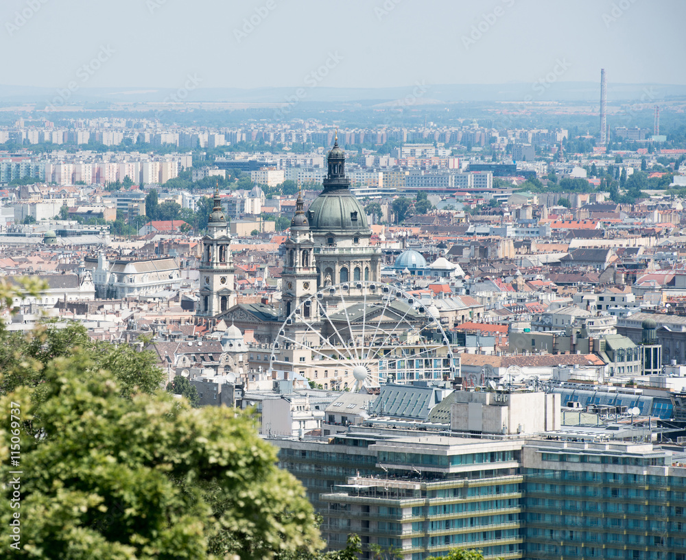 view of St. Stephens Basilica Big dome and Ferris wheel above rooftops in Budapest, Hungary, aerial photo