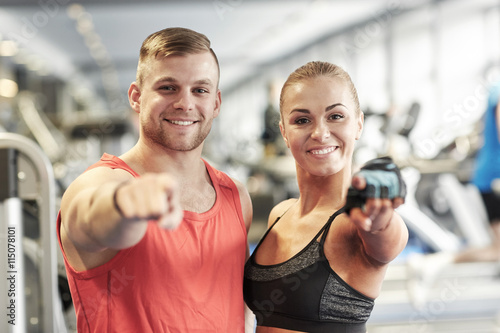 happy man and woman pointing finger to you in gym