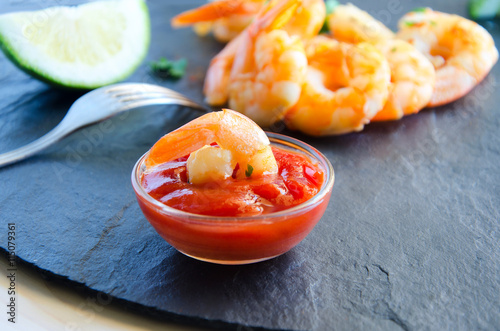 Grilled prawns with spicy sauce, lime and parsley on black background