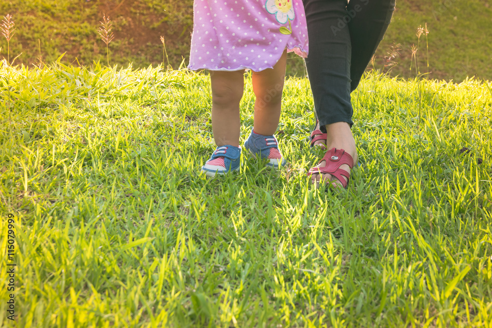 Blurred of first steps of baby with mother support ,concept for toddler move Blurred of first steps of baby with mother support ,concept for toddler move