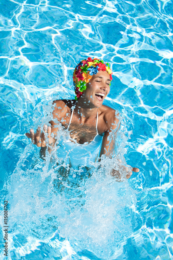 femme avec un bonnet de bain à fleurs qui rie dans une piscine