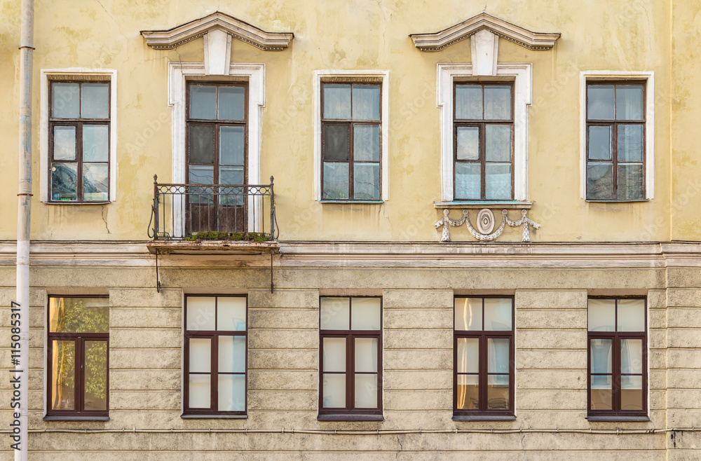 Several windows in a row and balcony on facade of urban apartment building front view, St. Petersburg, Russia.