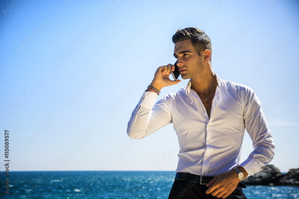 Young man at the seaside talking on cell phone Young man at the seaside talking on cell phone