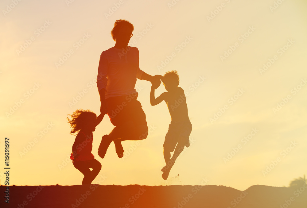 happy father with son and daughter jumping at sunset