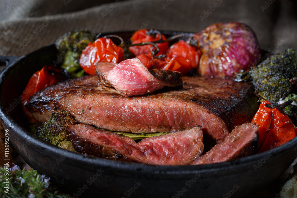 Beef steak with vegetables on a cast-iron frying pan