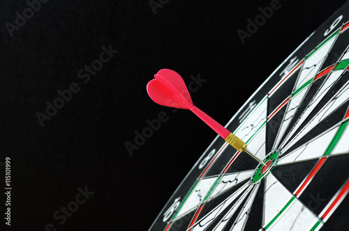 Red dart hitting on target with black background