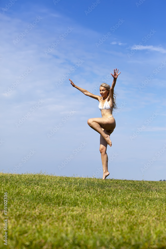 The happy woman in white bikini jumps in a summer green field against the blue sky. The happy woman in white bikini jumps in a summer green field against the blue sky.