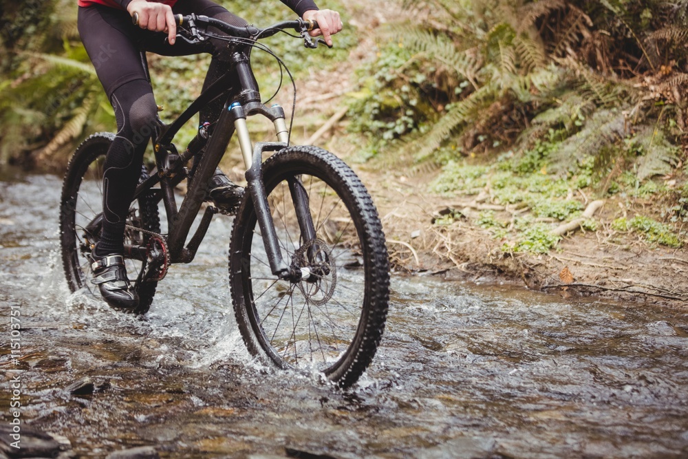 Mountain biker riding in stream Mountain biker riding in stream