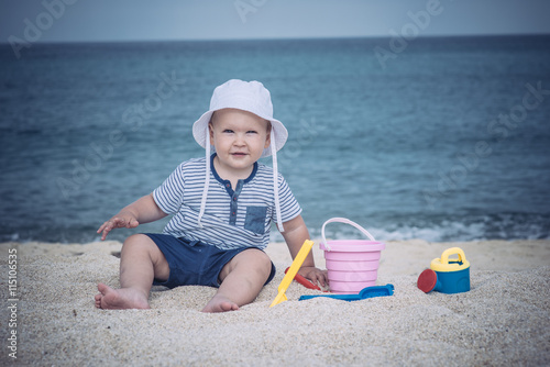 Toddler laughing sitting with toys and playing with sand