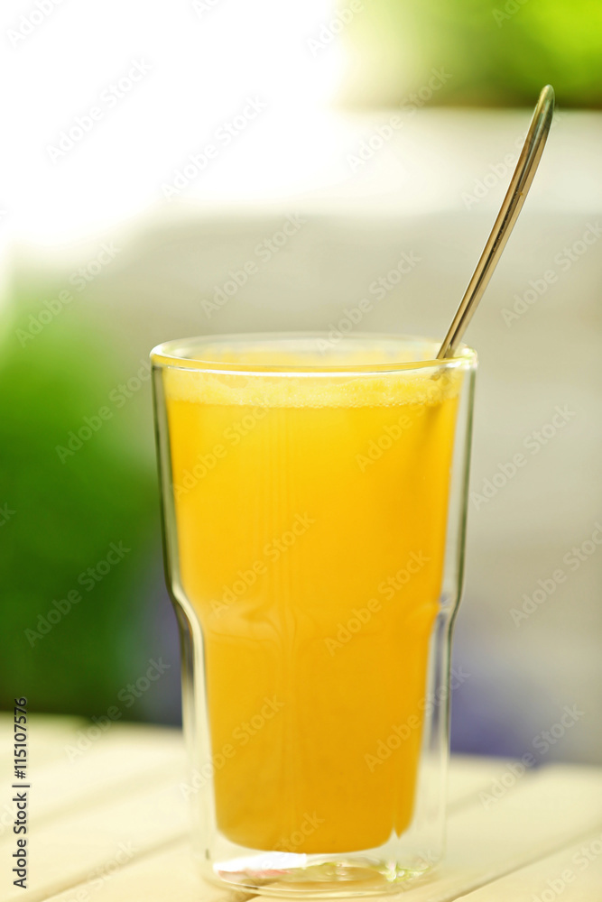 Full glass of juice with spoon on light wooden table Full glass of juice with spoon on light wooden table