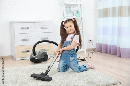 Cute little girl using vacu...