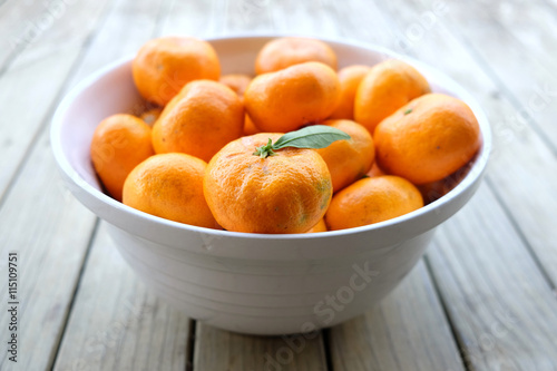 Imperfect satsuma mandarins - organic fruit produce - in a white bowl on a wooden background. Photographed with shallow depth of field in New Zealand.