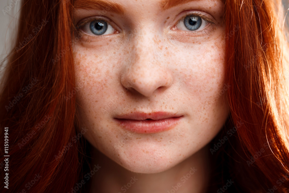 Portrait of young beautiful ginger girl over gray background. Portrait of young beautiful ginger girl over gray background.