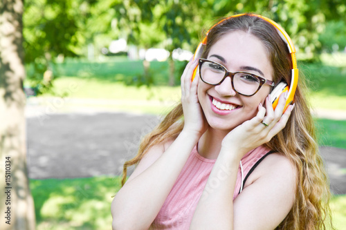 young girl listen music with headphone in the park