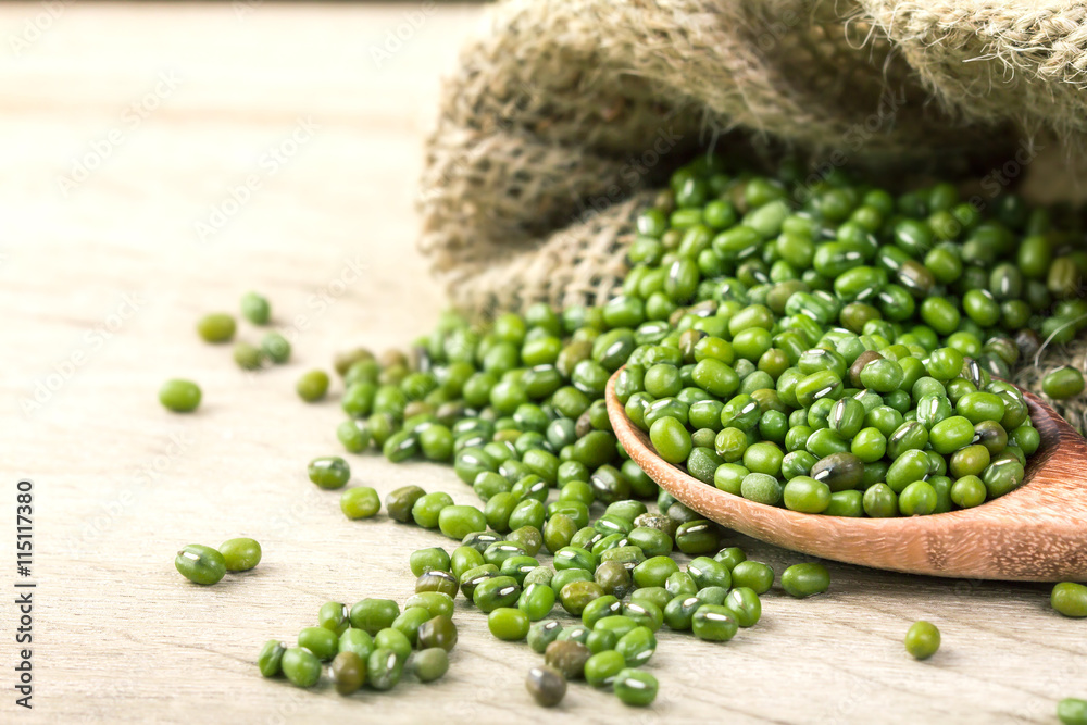 close up green mung beans in wooden spoon on wood plate close up green mung beans in wooden spoon on wood plate