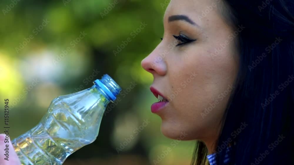 Slowmotion detail of young beautiful woman stands and drinks from plastic bottle Slowmotion detail of young beautiful woman stands and drinks from plastic bottle