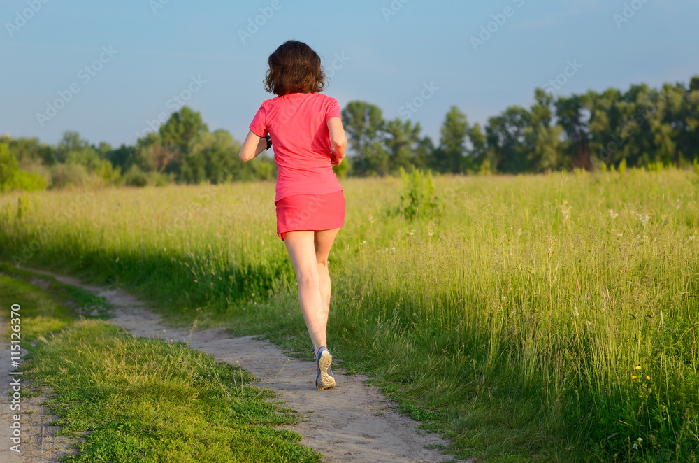 Woman runner jogging on trail outdoors, spring running and exercising
