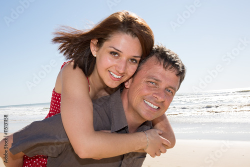Love - Happy couple on beach having fun piggyback ride