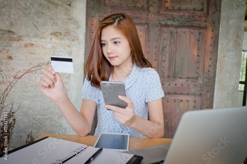 Photo of a beautiful young female shopping online and paying with a credit card. Credit card information is fictitious. photo