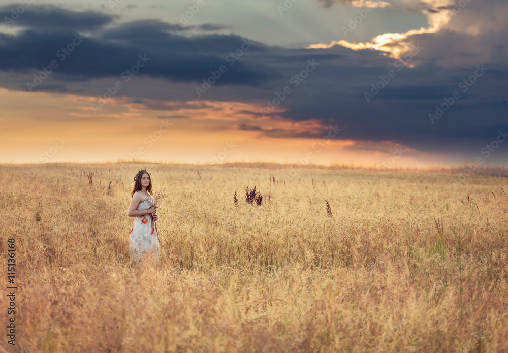 Portrait of a young woman in a wheat field, at sunset