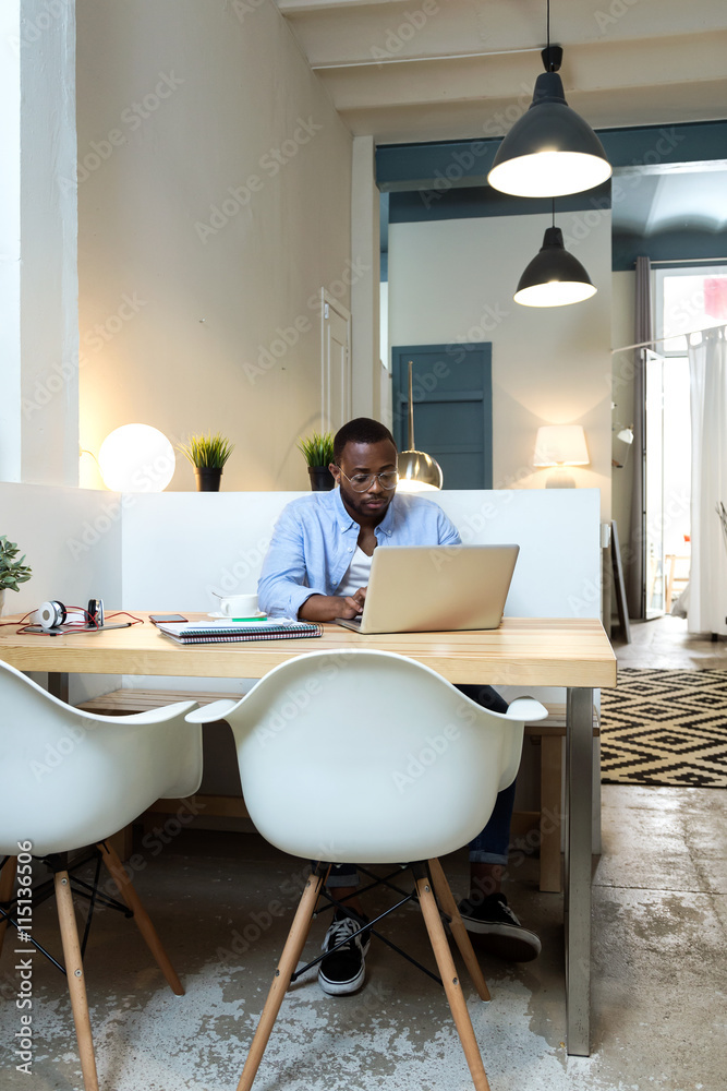Handsome young black man working with laptop at home.