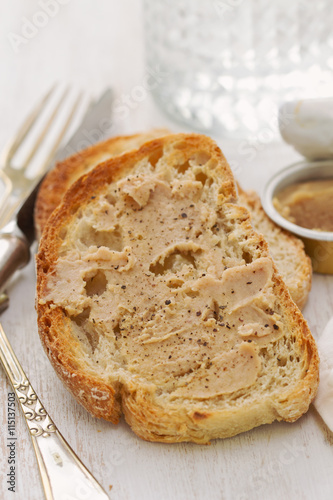 bread with pate and glass of water on white wooden background