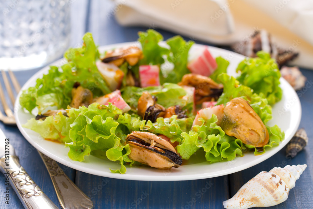 seafood salad on white dish and glass of water on blue wooden background