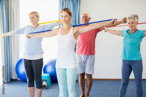 Instructor and seniors exercising with stretching bands