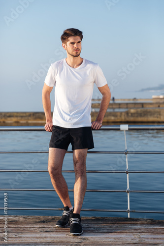 Handsome young sportsman standing on pier